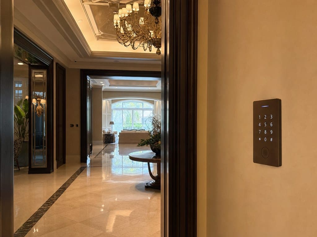 Emirates Hills mansion entrance hall at twilight with custom matte-bronze keypad and warm chandelier scene lighting