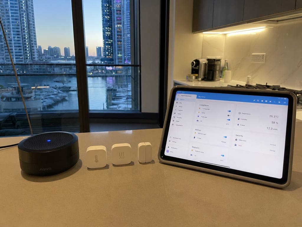 Dubai Marina apartment kitchen counter with Aqara hub, sensors and a tablet showing the Home Assistant dashboard at evening