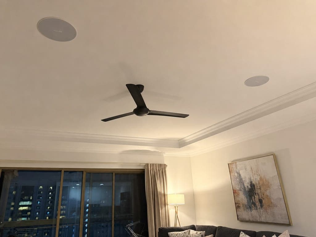 In-ceiling Sonos speakers in a Sharjah apartment living room with the kitchen and dining visible behind