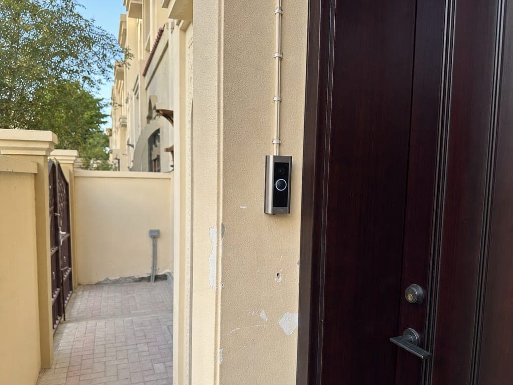 Smart video doorbell and front-door camera setup at a Sharjah townhouse entrance, Bayora install panel visible
