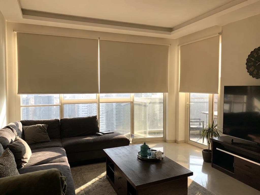 Lutron motorized blinds half-open in an Abu Dhabi living room with afternoon sun filtered through