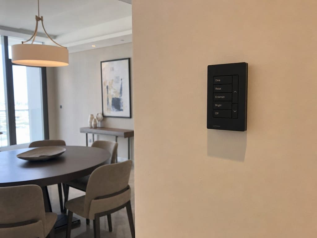 Lutron Palladiom keypad in matte black on a dining-room wall, scene lighting visible behind