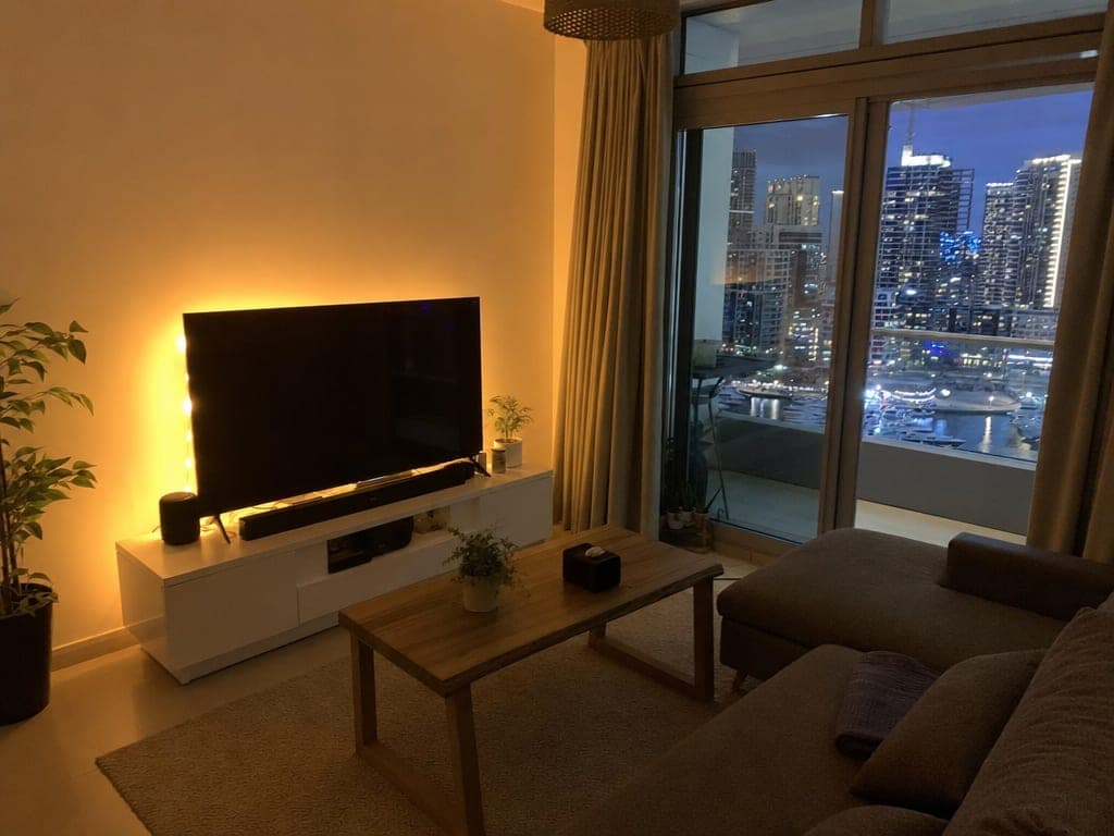 JLT apartment living room at evening with Philips Hue color lighting set to warm scene and accent strips behind TV