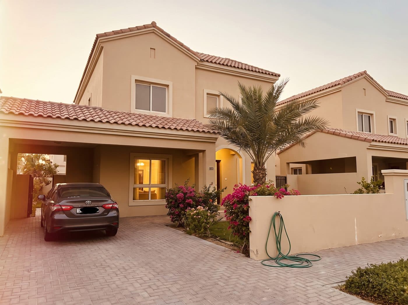 Two-storey Springs villa in Dubai with terracotta roof tiles and a bougainvillea front garden at golden hour